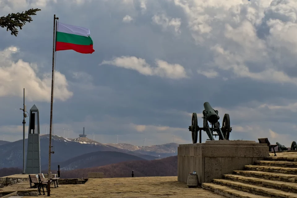 A flag pole and a gun infront of the Shipka monument