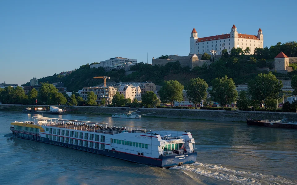 A river cruise liner is passing by the castle.